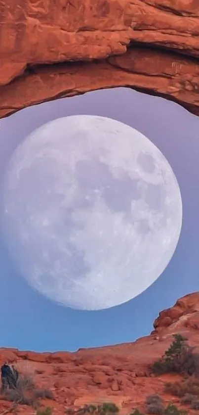 Full moon framed by a red rock arch under a clear sky.