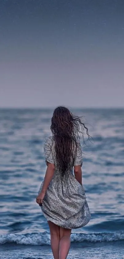 Woman by the sea at night with a moonlit sky background.