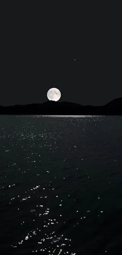 Full moon over water with mountains at night.