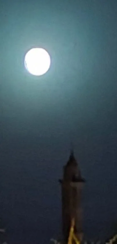 Full moon shining in a dark, serene night sky over a silhouette of a tower.