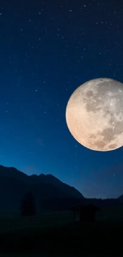 Full moon over mountain at night with starry sky in background.