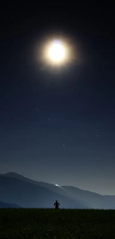 Silhouette under a bright moon on a clear night with hills.