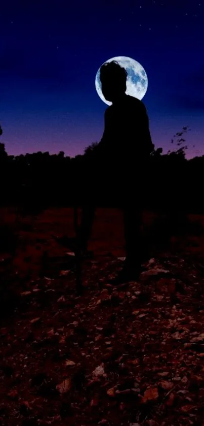 Silhouette standing under a full moon in a dark blue night sky.