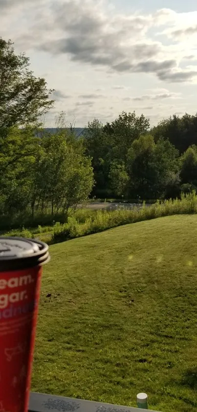 Serene landscape with coffee cup in foreground, lush with greenery.