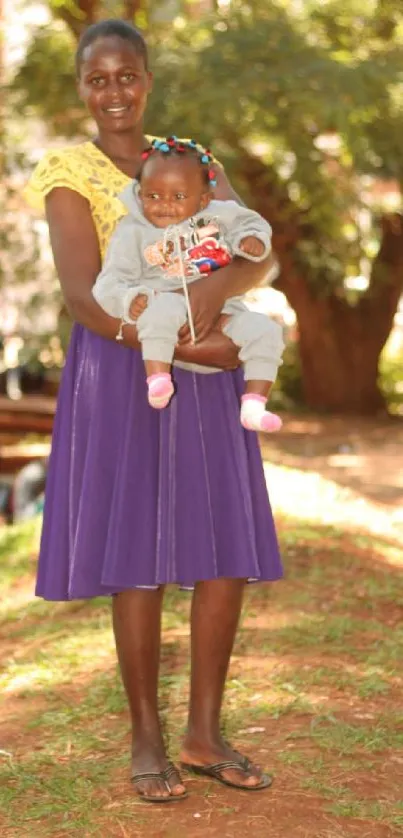 Mother holding baby in sunny park setting.