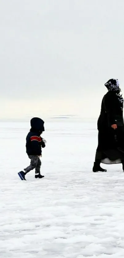 Mother and child walking on a snowy landscape in winter.