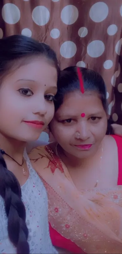 Mother and daughter posing in traditional attire with warm expressions.