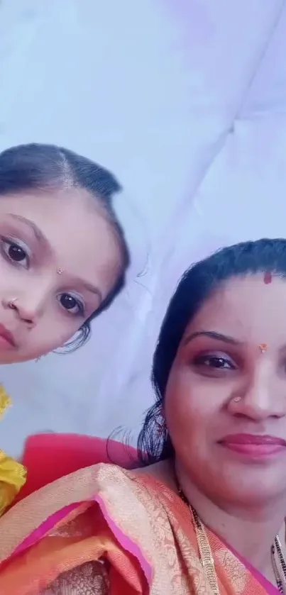 Mother and daughter in traditional attire smiling warmly.