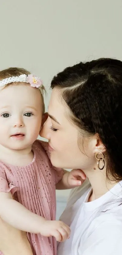 Mother kisses baby in serene wallpaper setting.