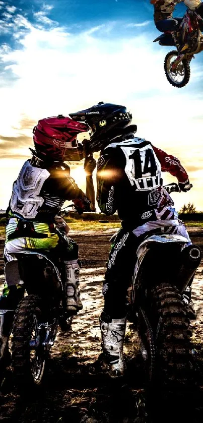 Motocross bikers in action under a vibrant sunset sky.