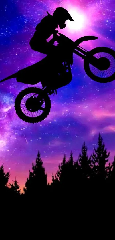 Silhouette of a motocross rider jumping against a purple galaxy sky.