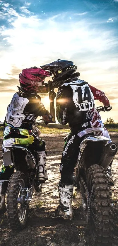 Two motocross riders share a sunset moment.