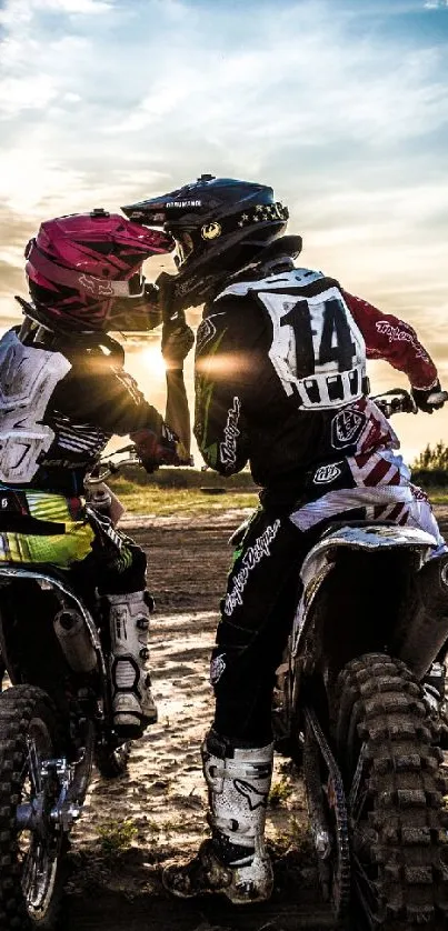 Motocross riders embrace at sunset scene.