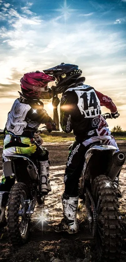 Motocross riders sharing a moment at sunset.