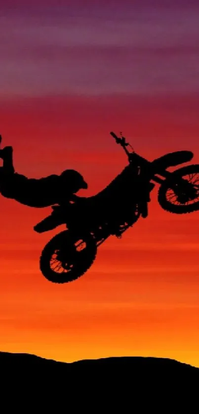 Silhouette of motocross jump against vibrant sunset sky.