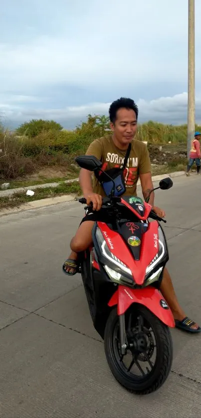 Person riding a vibrant red motorbike on a scenic road.