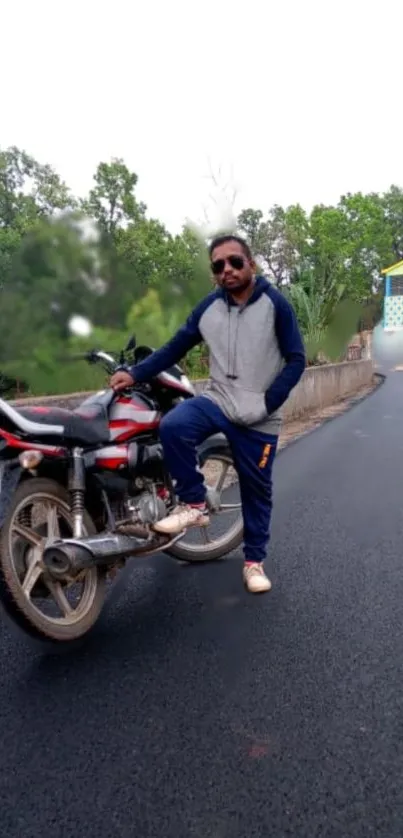 Person posing with motorbike on open road.