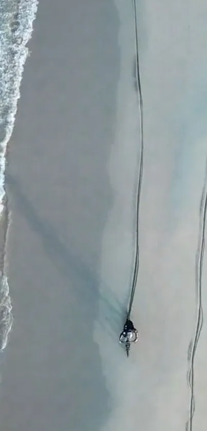 Aerial view of a motorbike on a sandy beach with turquoise waves.