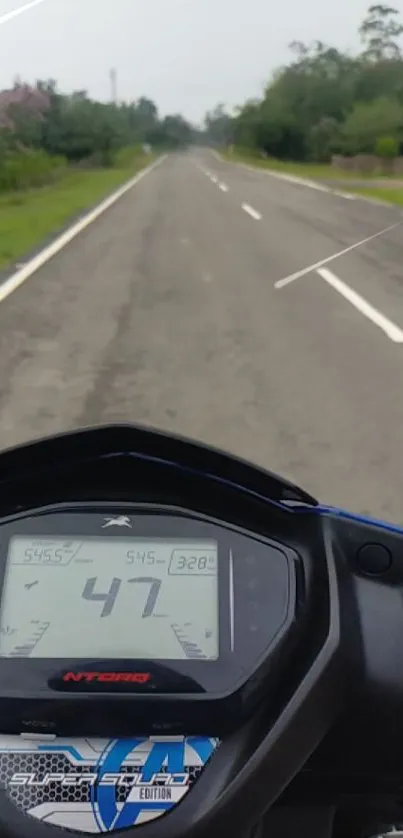 Motorbike dashboard view on open road with surrounding greenery.