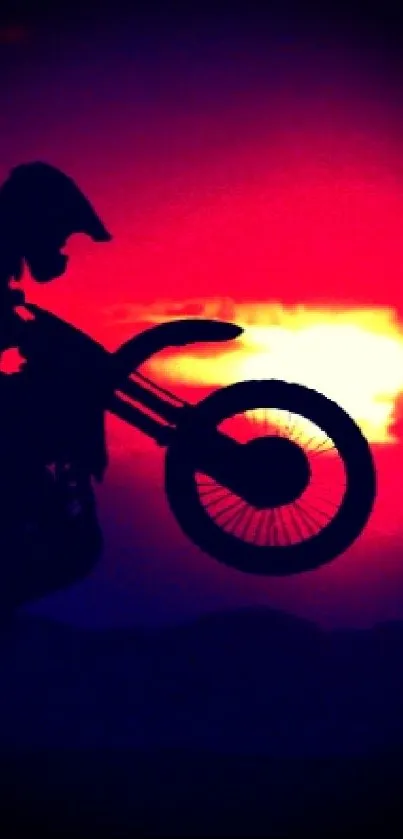 Silhouette of a motorbike against a crimson sunset sky, creating an energetic and dynamic scene.