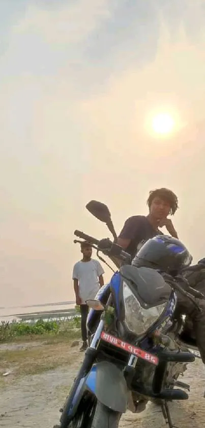 Man on a motorcycle at sunset with scenic horizon.