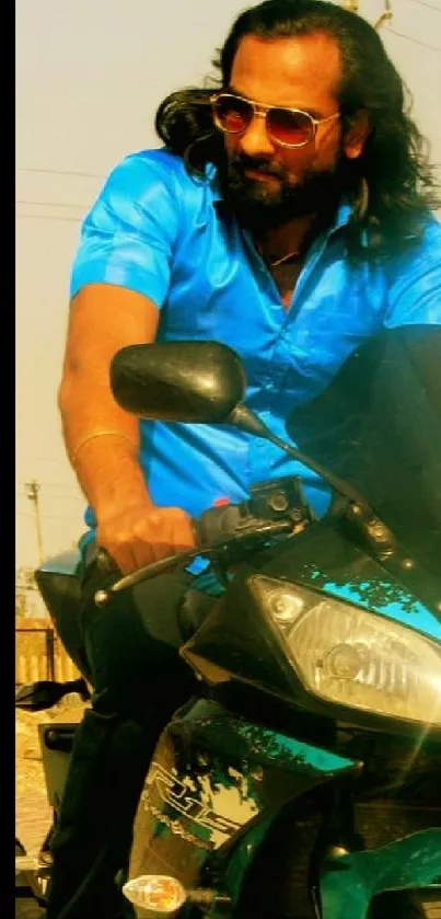 A biker in a blue shirt riding a motorcycle under the sun.