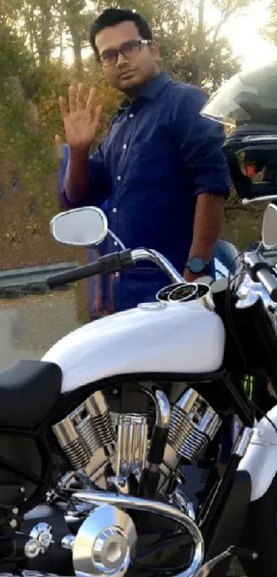 Person next to motorcycles on a scenic road with a green backdrop.