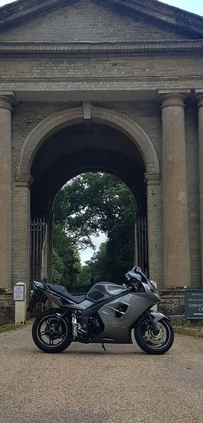 Motorcycle in front of historic stone pillars and archway.