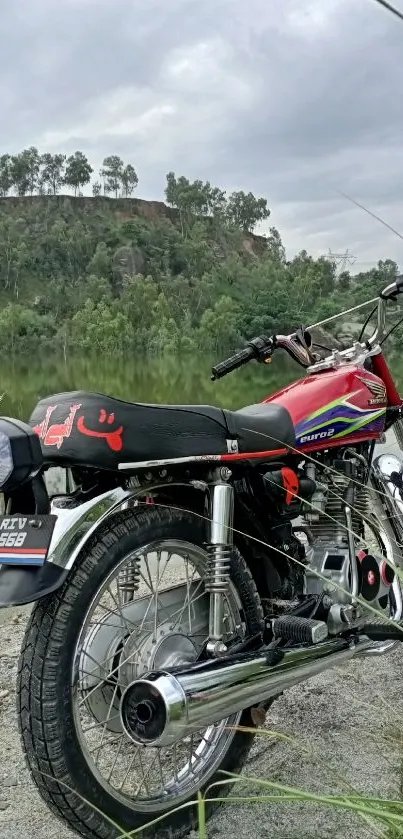 Classic motorcycle parked by the riverside surrounded by greenery.