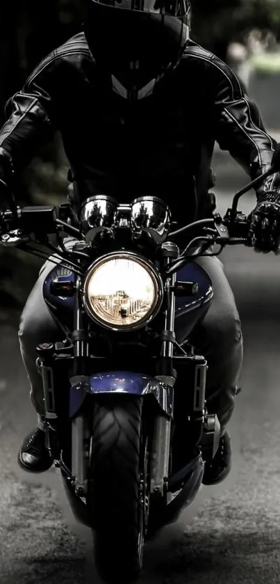 A motorcycle rider in black gear rides down a dimly lit road.