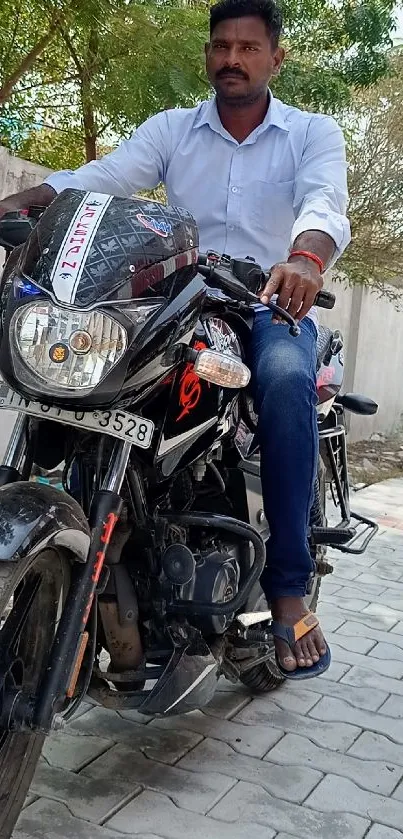 A man in a white shirt riding a motorcycle on a paved path.