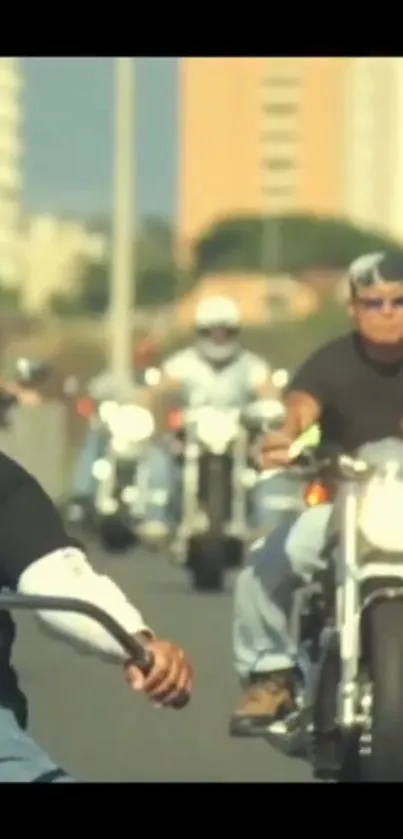 Group of bikers riding motorcycles down a sunny road.