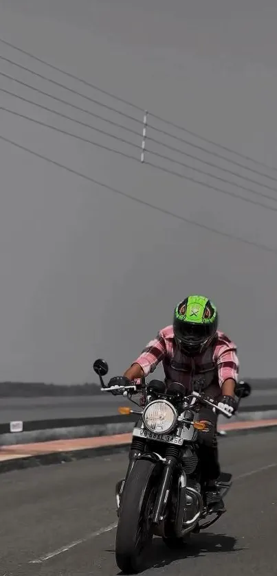 Motorcyclist with bright helmet on a grey road.