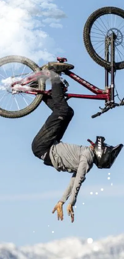 Cyclist performing a bike trick mid-air with mountains in the background.