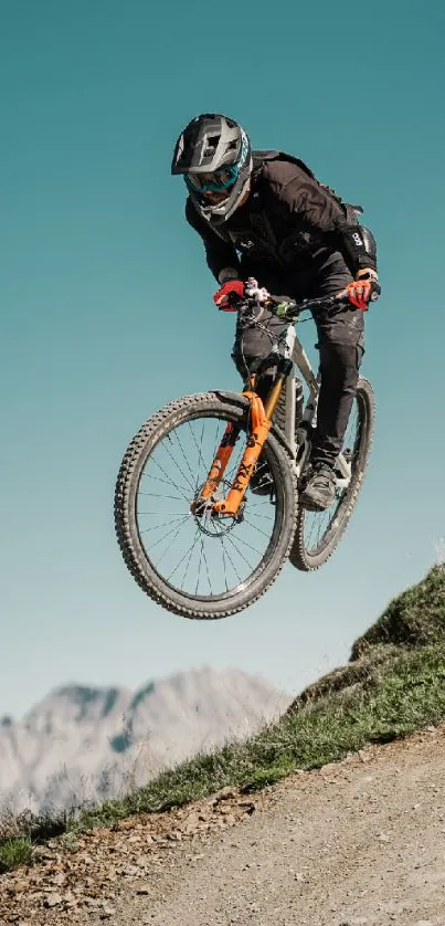 Mountain biker jumps on a scenic outdoor dirt trail against a blue sky.