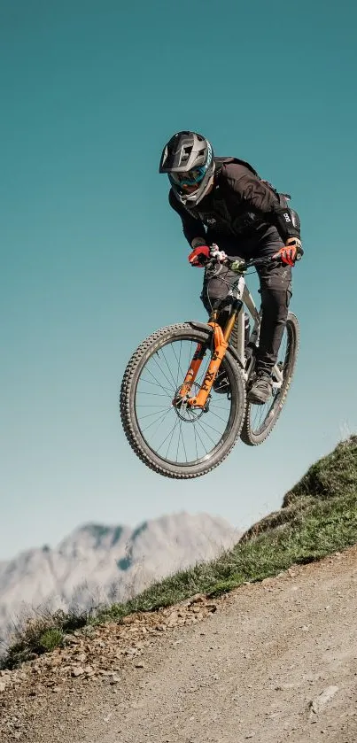 Mountain biker jumps on trail with scenic mountain backdrop.