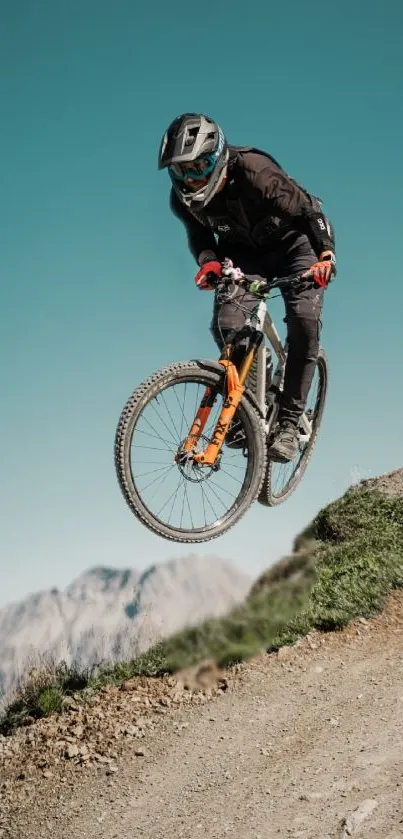 Cyclist in mid-air jump on mountain trail with scenic backdrop.