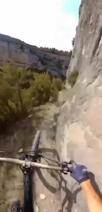 Mountain biker on rocky trail beside a steep cliff.