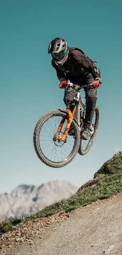 Cyclist jumps mid-air on a mountain trail with a scenic view.