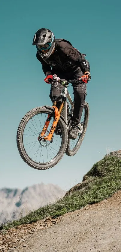 Cyclist jumps on mountain trail under a clear blue sky.