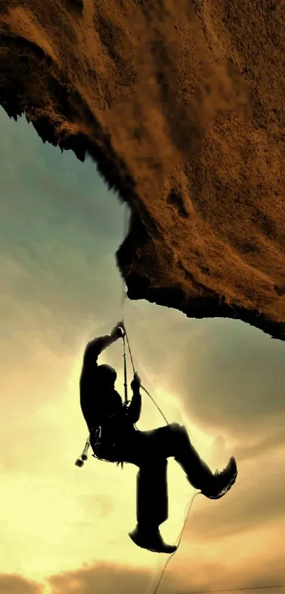 Silhouette of a rock climber against a warm orange sunset sky on a mountain.