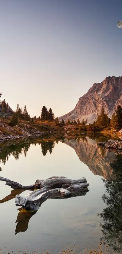 Serene mountain lake with dusk sky and moon reflecting on water.