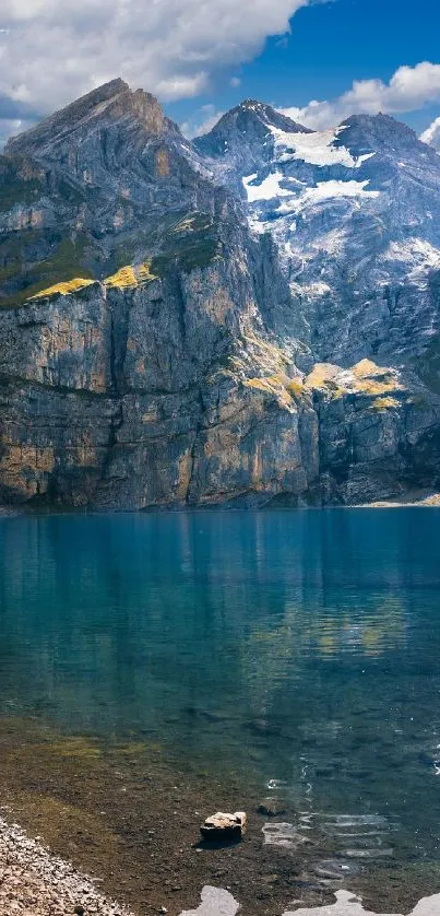 Tranquil mountain lake with blue sky and rocky peaks.