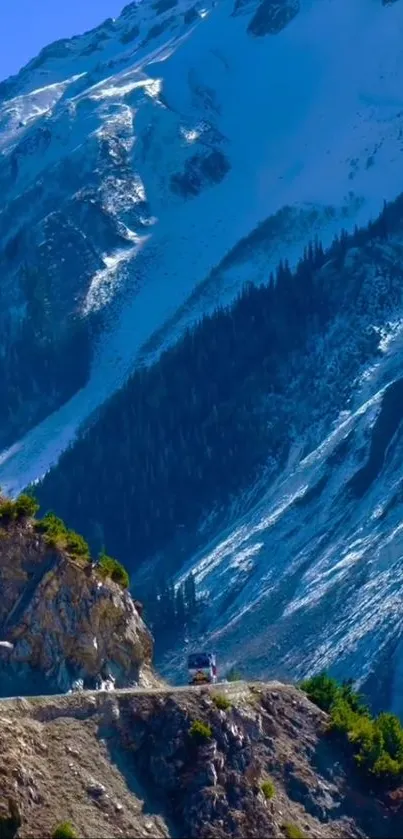 Scenic mountain road with snow-capped peaks and green trees.