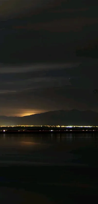 Night-time mountain landscape with dark sky and calm waters.