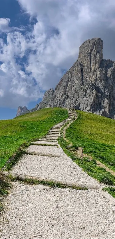 Serene mountain path leading to a rocky peak under a cloudy sky.