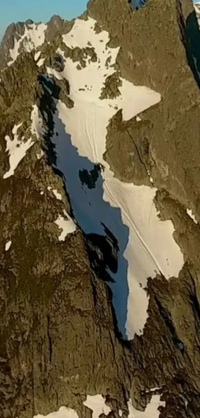 Brown mountain peaks with snow patches at sunrise.