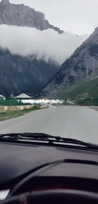 Mountain road view with serene surroundings from a car dashboard.