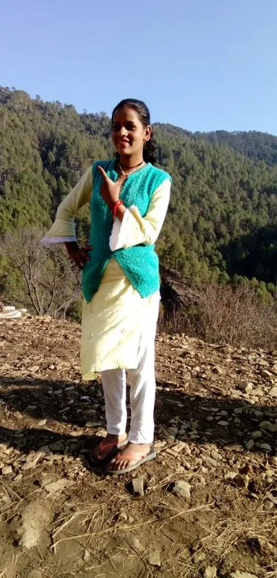 Girl posing in a stylish outfit with a mountain and forest background.