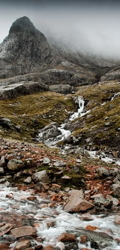 Mountain stream flowing through rugged landscape with misty peaks.